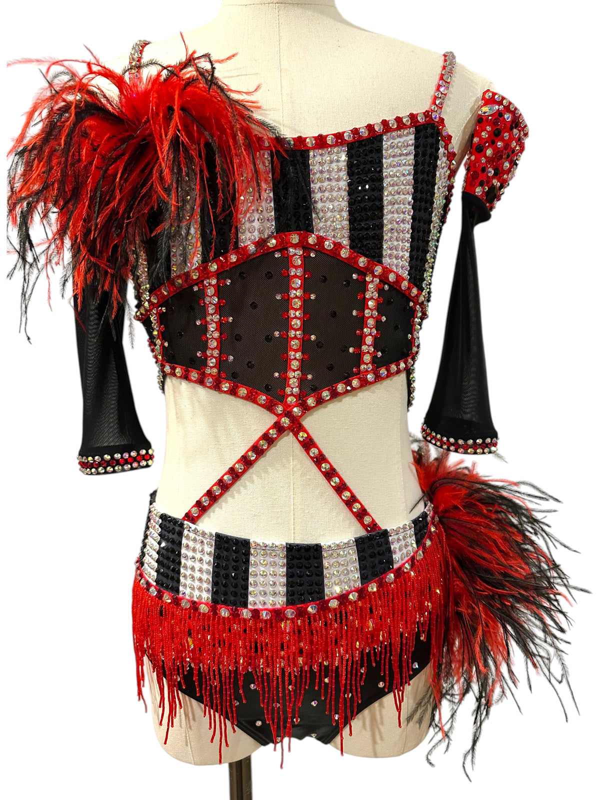 Front view of a ready-to-ship red, black and white rhinestone competition dance costume featuring striped bodice, feather shoulder accent, beaded fringe, and sheer mesh details.