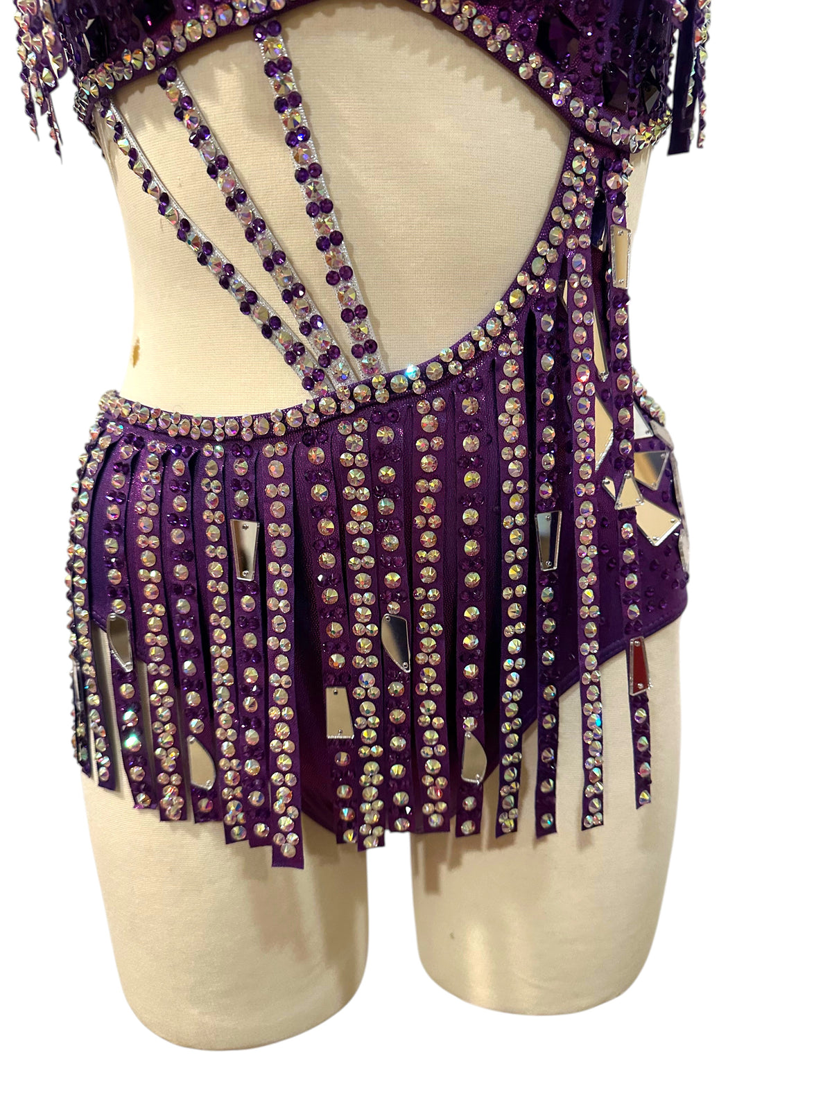 Close-up of hologram purple dance costume featuring mirror accents, rhinestone embellishments, and intricate competition costume detailing.