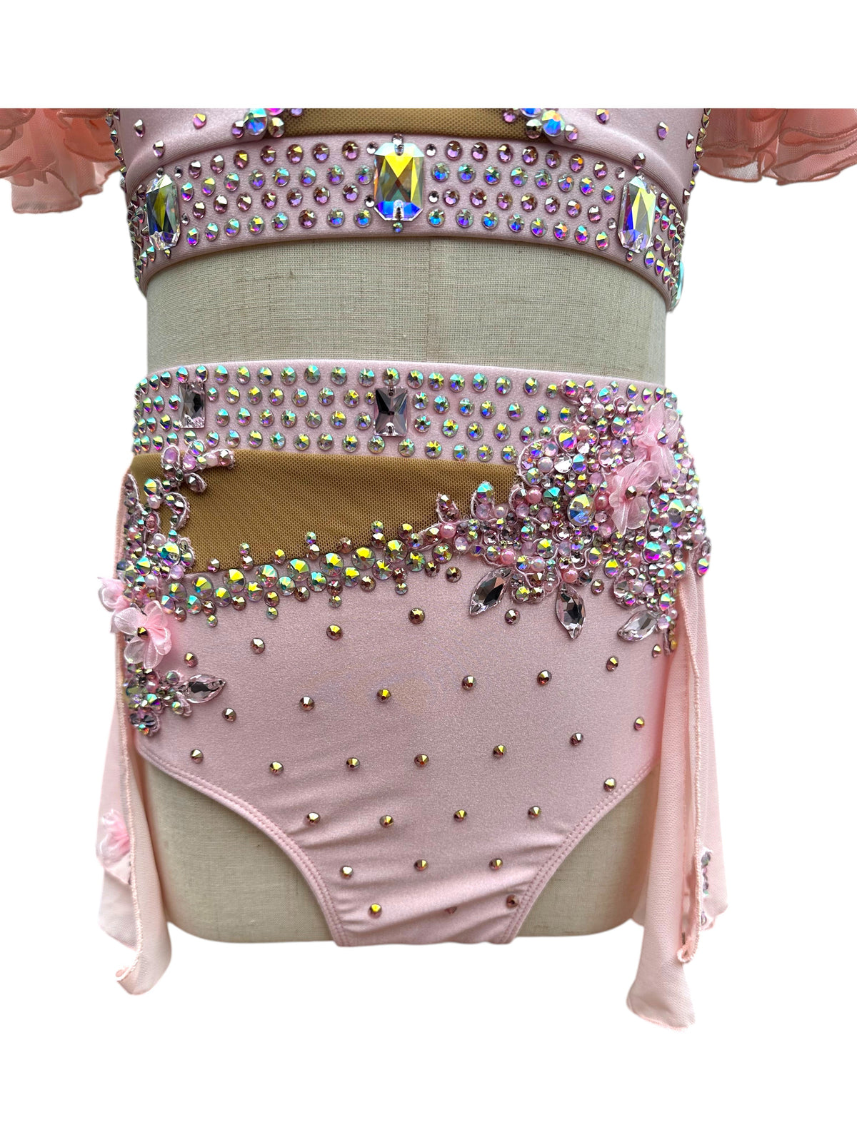Close-up of blush pink dance costume bottom with rhinestone embellishments and floral detailing