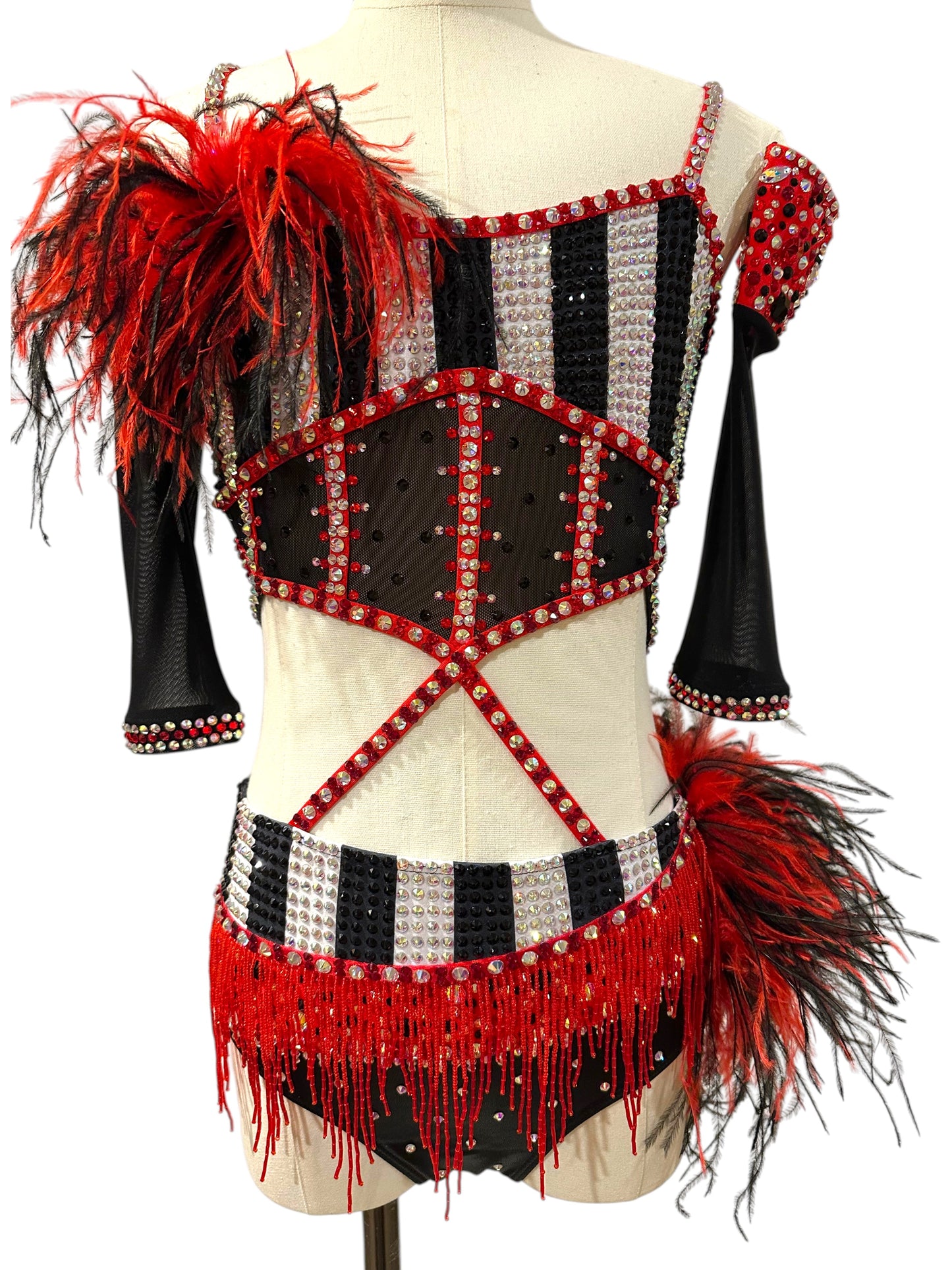 Front view of a ready-to-ship red, black and white rhinestone competition dance costume featuring striped bodice, feather shoulder accent, beaded fringe, and sheer mesh details.