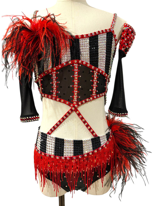 Front view of a ready-to-ship red, black and white rhinestone competition dance costume featuring striped bodice, feather shoulder accent, beaded fringe, and sheer mesh details.