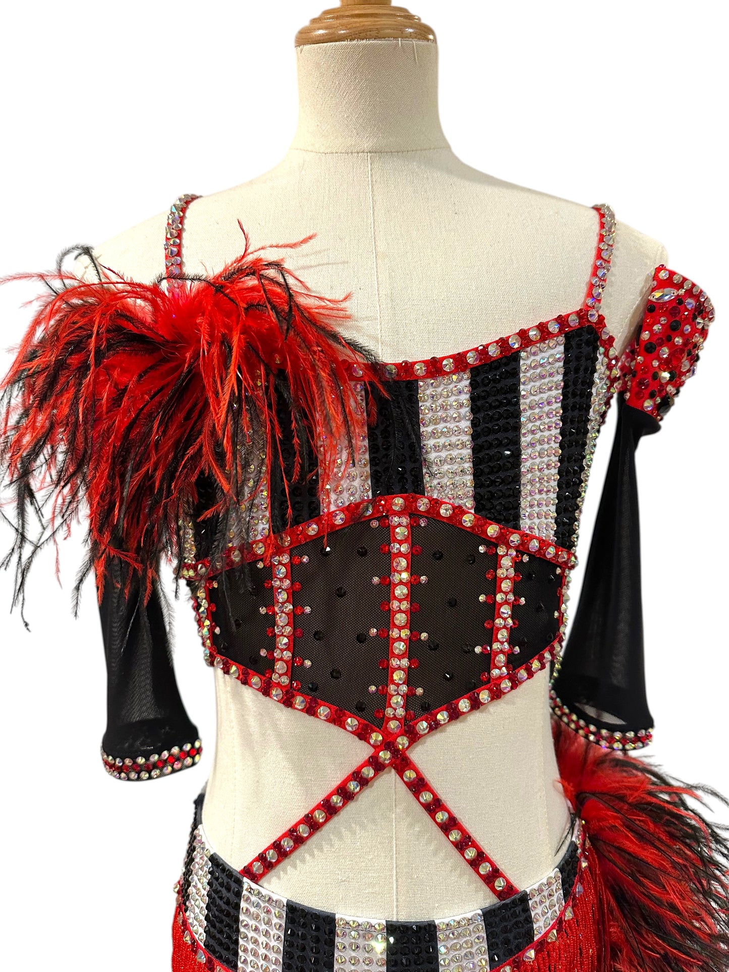 Close-up front view of a red, black and white rhinestone dance costume highlighting striped bodice, feather shoulder detail, and sparkling crystal embellishments.