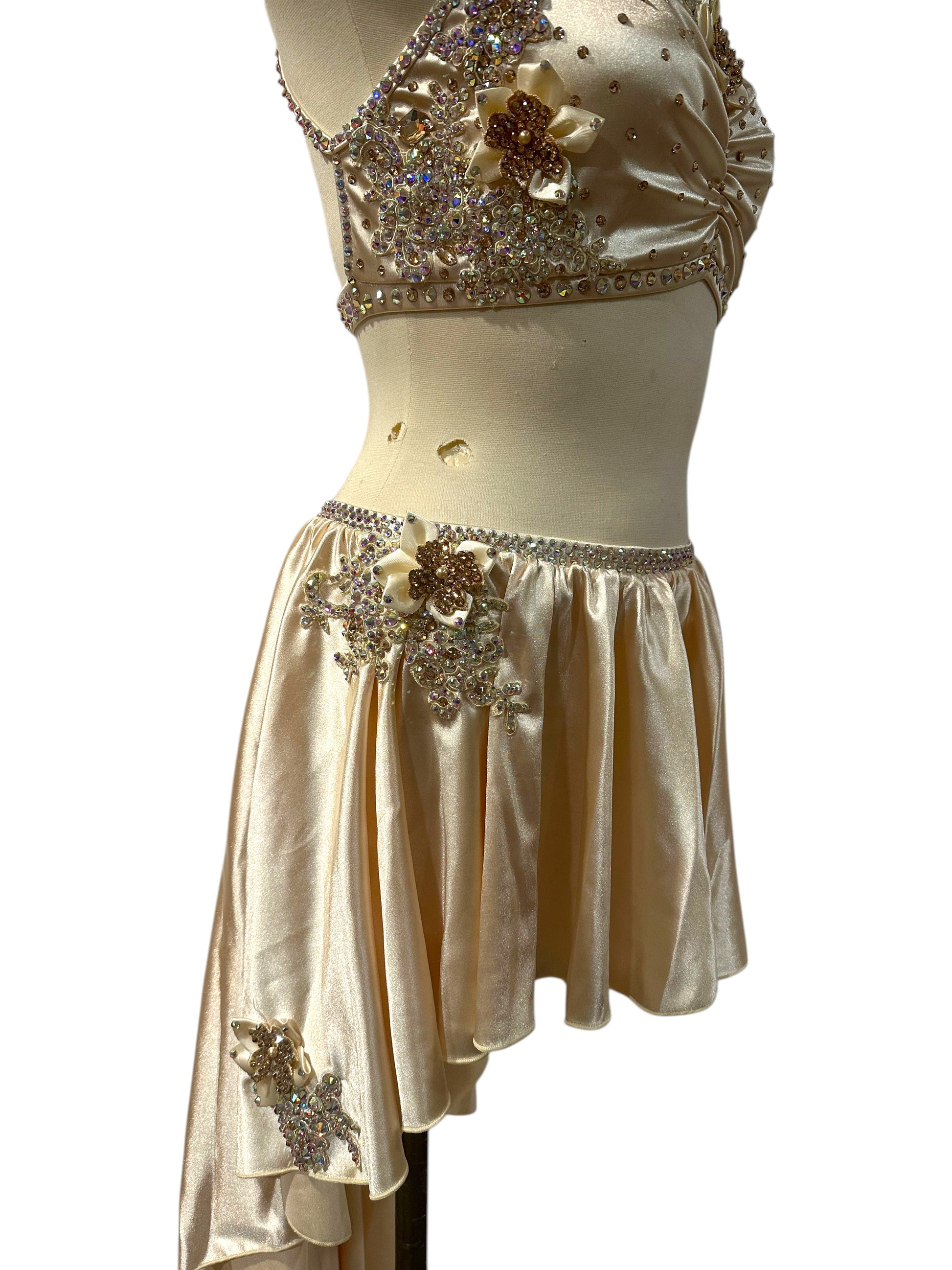 Close up of right side view of the Aubrey Ready-to-Ship dance costume featuring elegant draping, floral crystal embellishments, and a layered asymmetrical skirt.