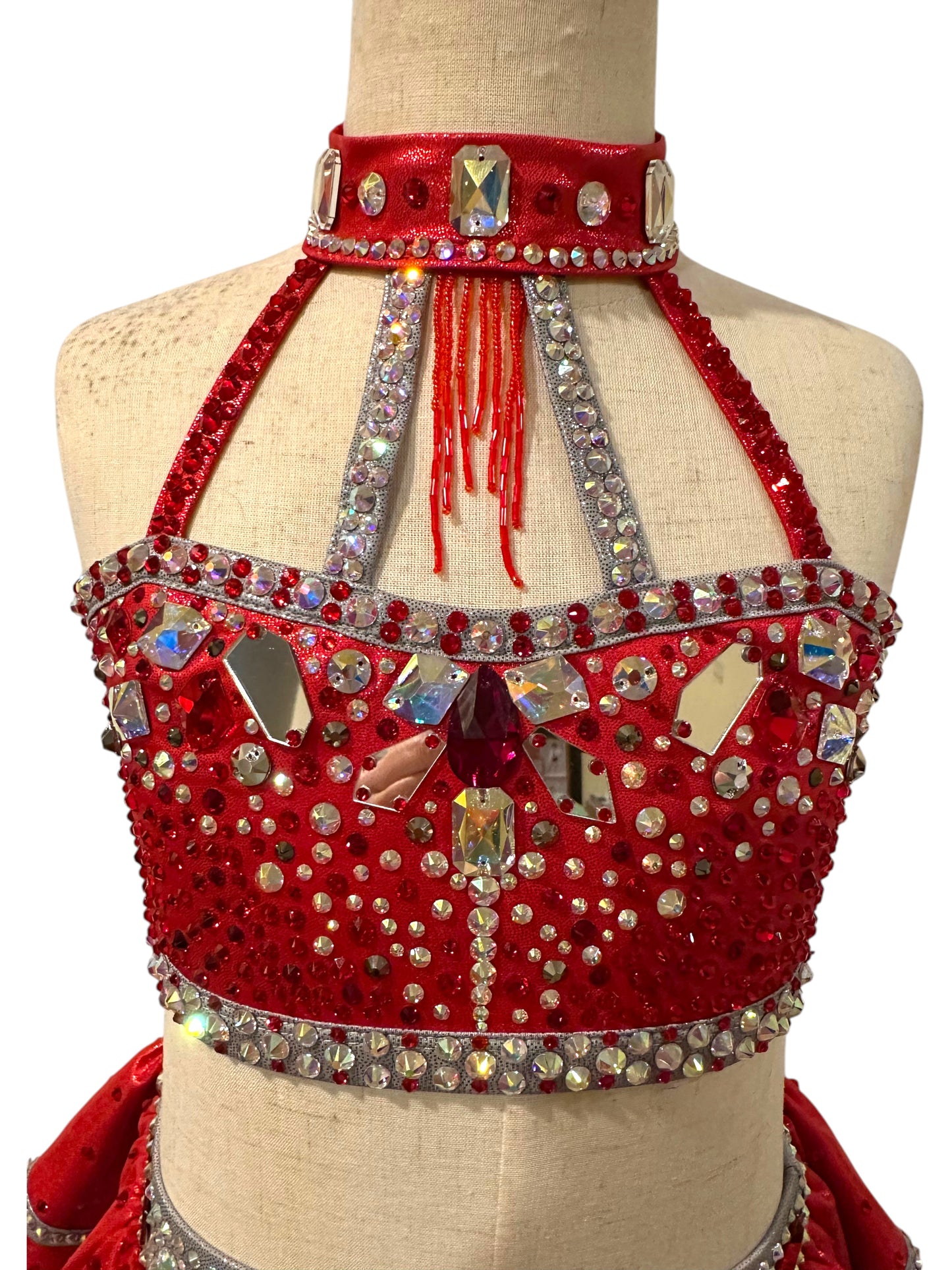 Close-up of the Kiki Ready-to-Ship costume featuring red metallic fabric, oversized crystal stones, rhinestones, and high-neck detailing.