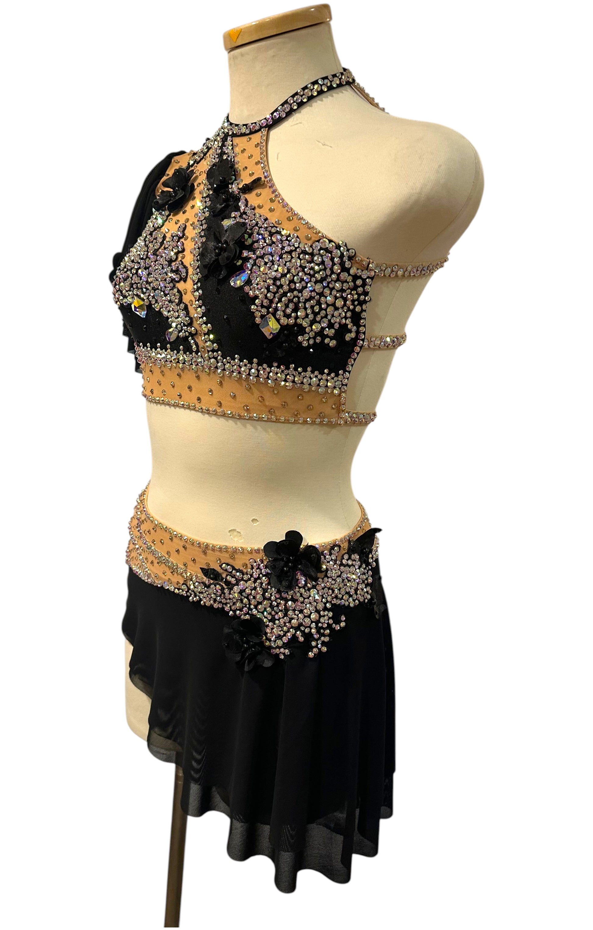 Angled view of Scarlett black and nude dance costume with rhinestones, floral appliqués, and layered shoulder draping.