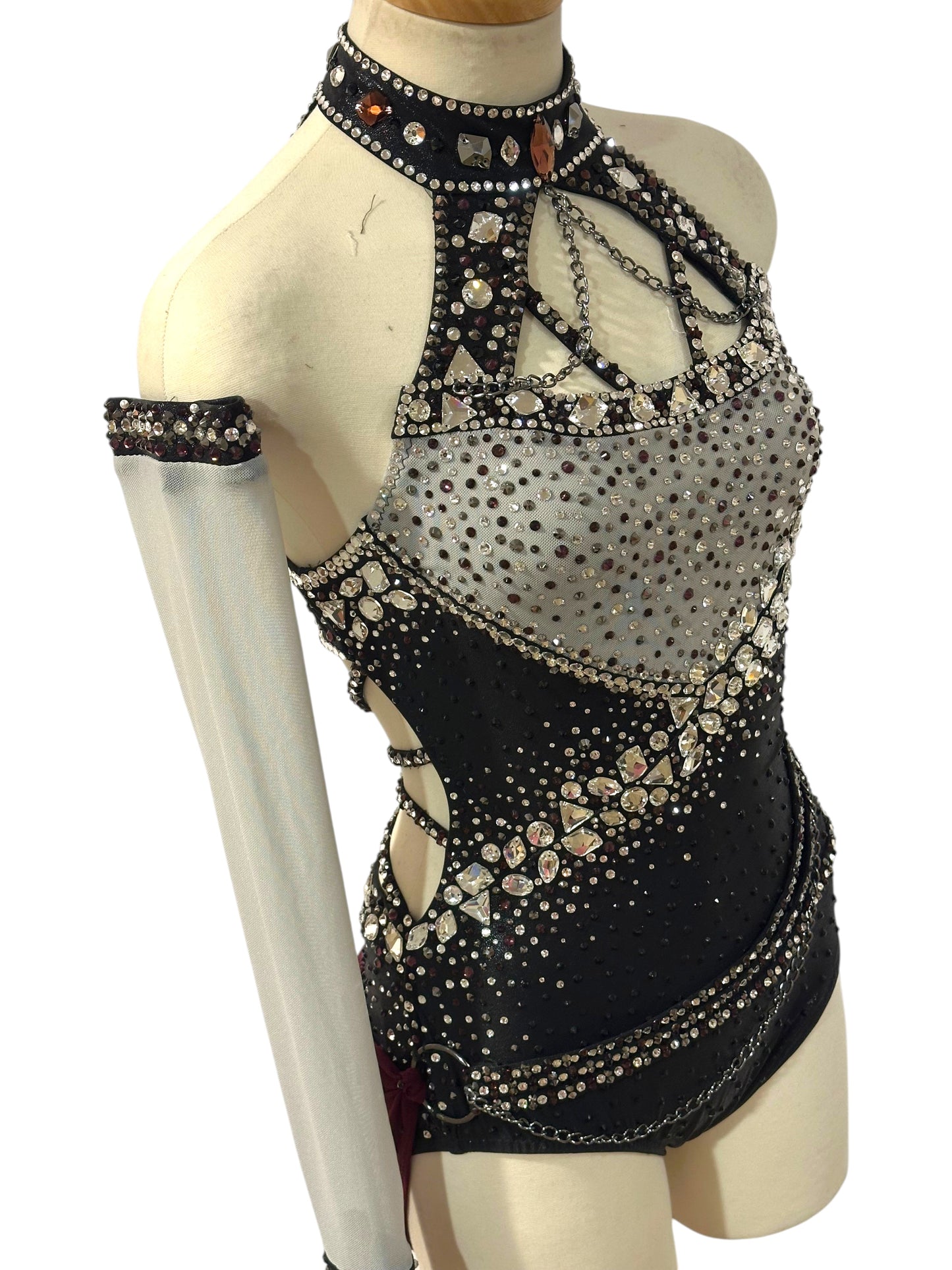 Angled view of black and silver Ready-to-Ship dance costume with rhinestones, statement crystals, detached sleeve and burgundy mesh drape.