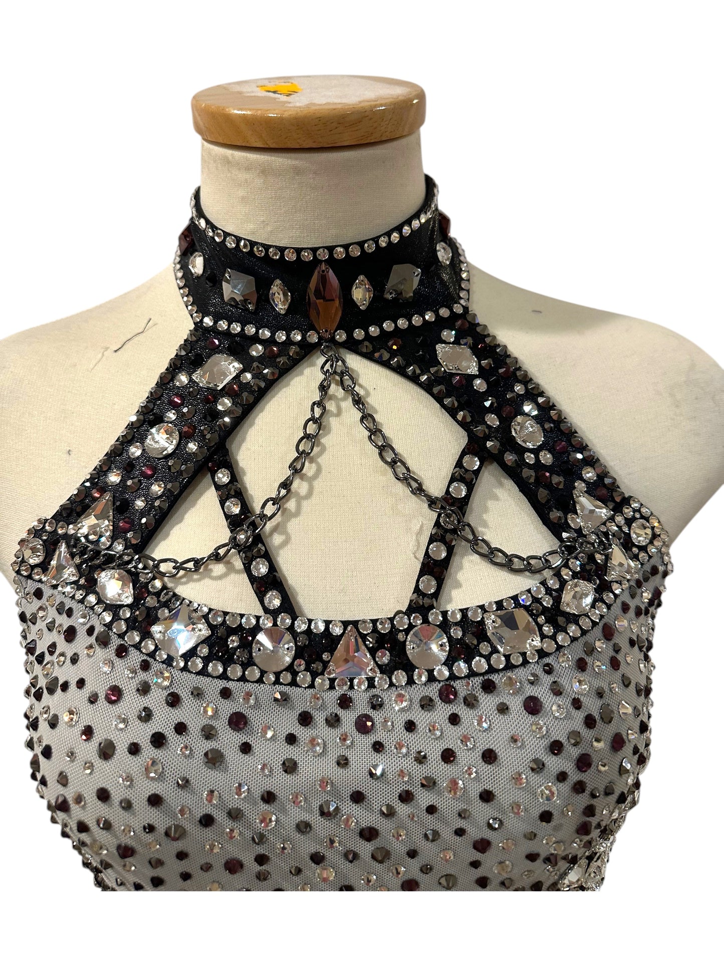 Close-up of black and silver dance costume bodice with high neckline, crystal embellishments, rhinestones and metallic chain accents.