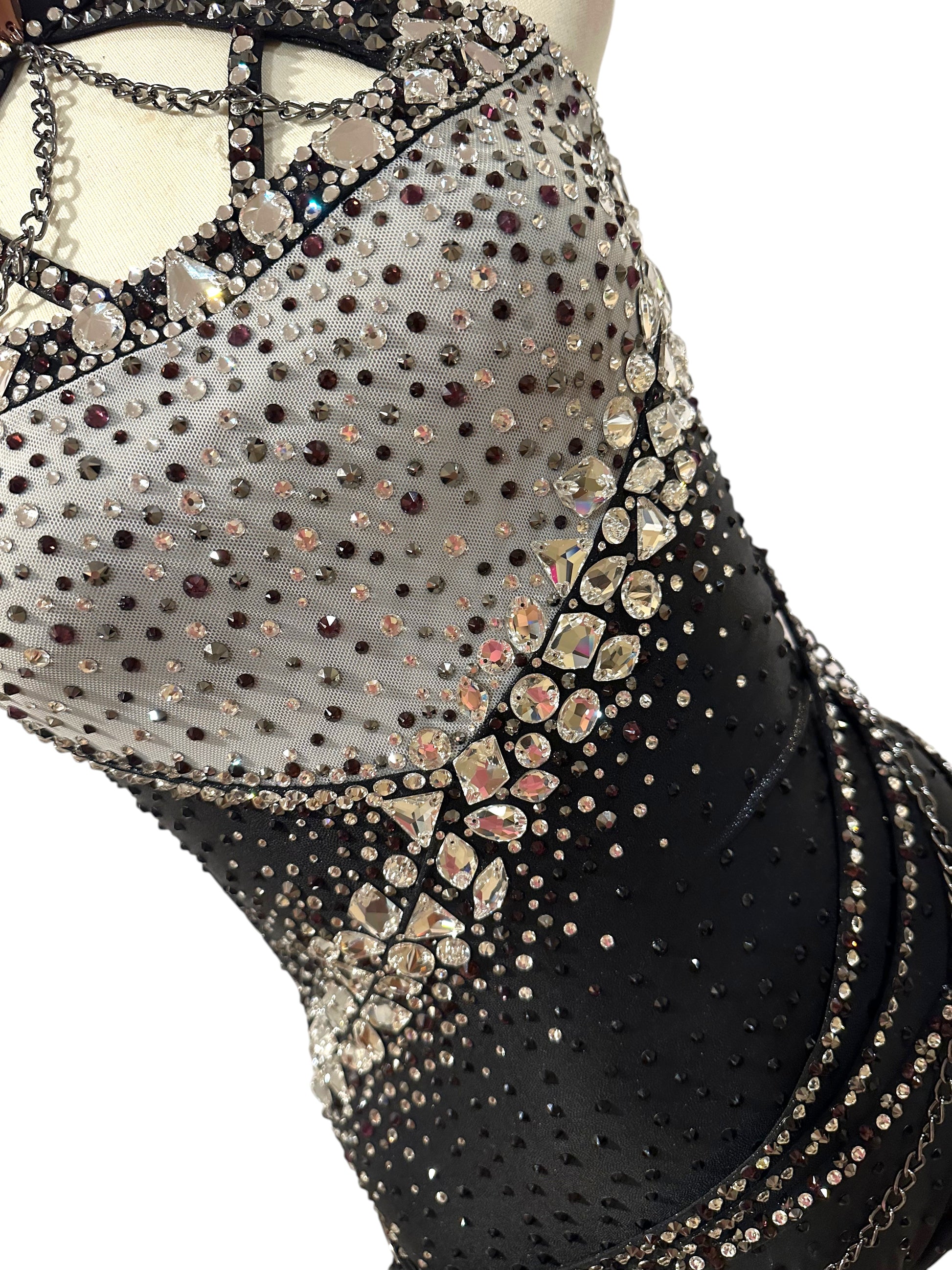 Close-up of silver mesh and black dance costume bodice with hand-applied rhinestones, statement crystals and geometric detailing.