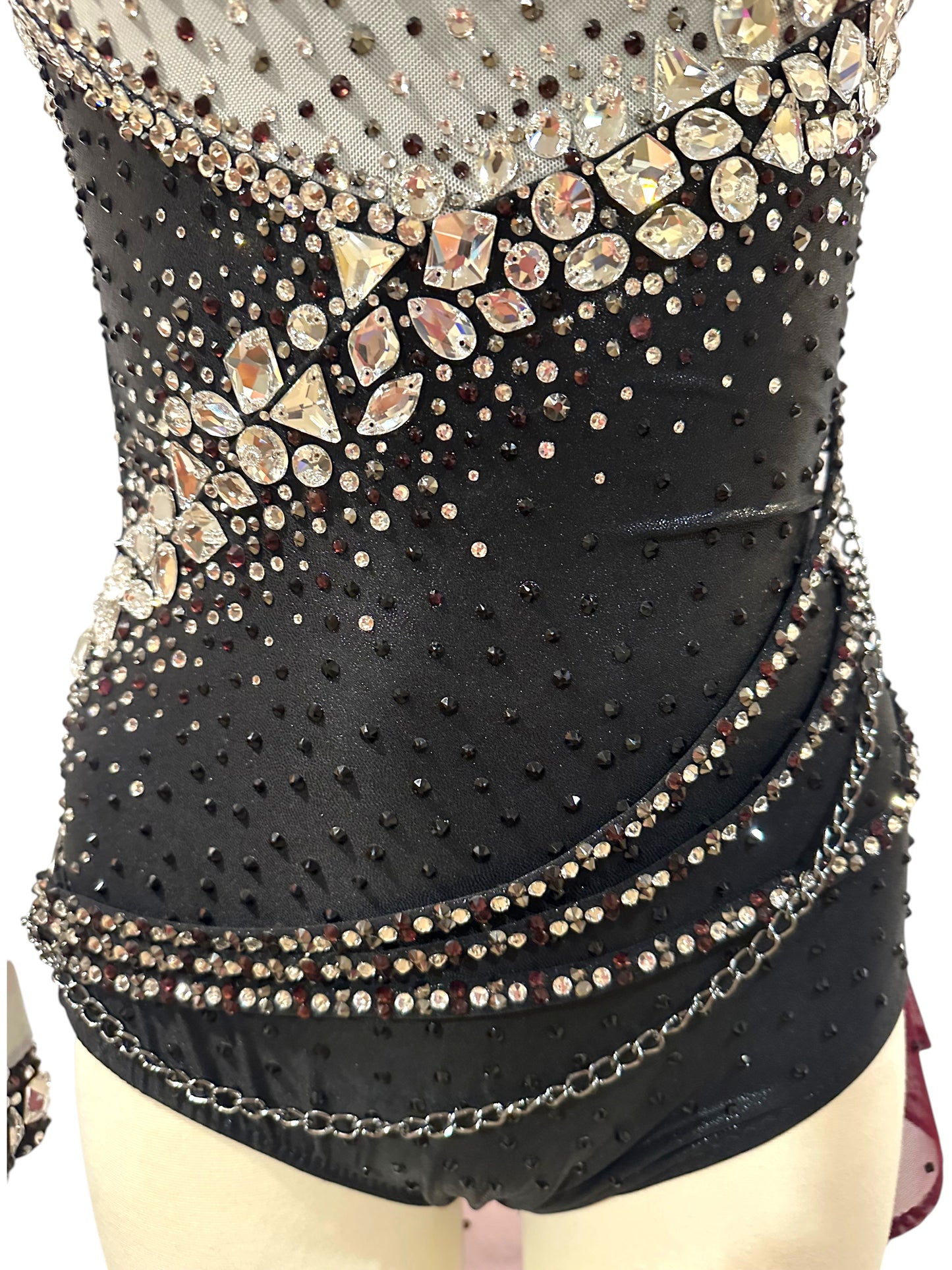 Close-up of black dance costume waist with crystal embellishments, rhinestone trim and metallic chain accents.