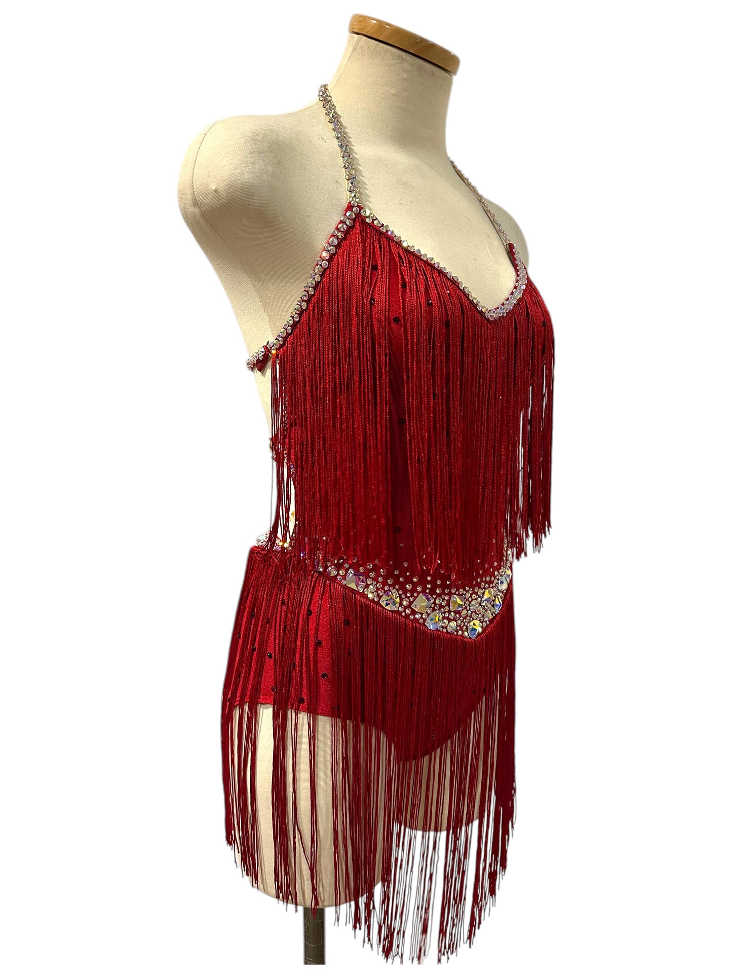 Angled view of red Ready-to-Ship dance costume showing flowing fringe, crystal detailing, halter neckline, and fitted silhouette.