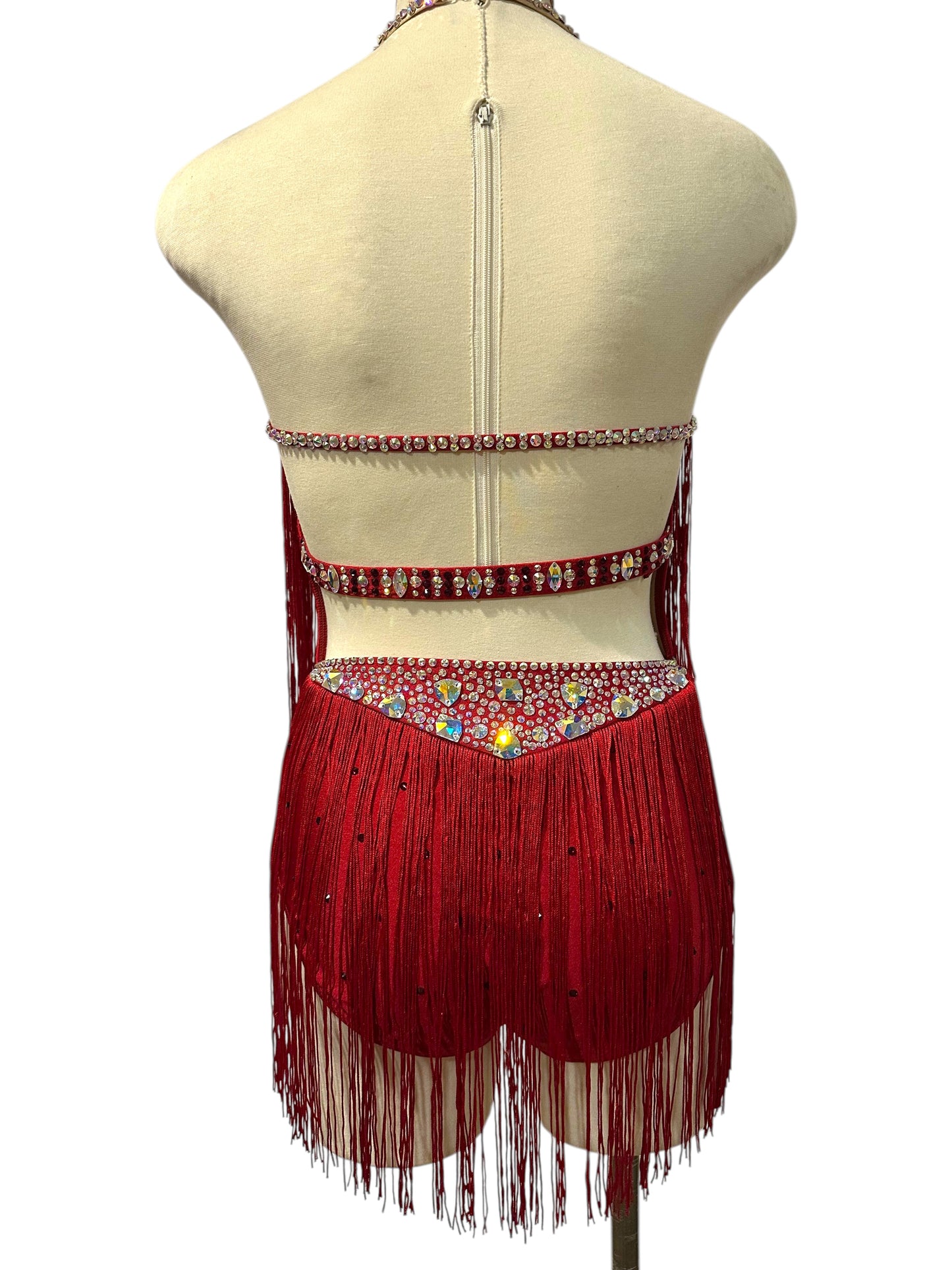 Back view of red Ready-to-Ship dance costume with open back, rhinestone straps, crystal waistband, and flowing red fringe.