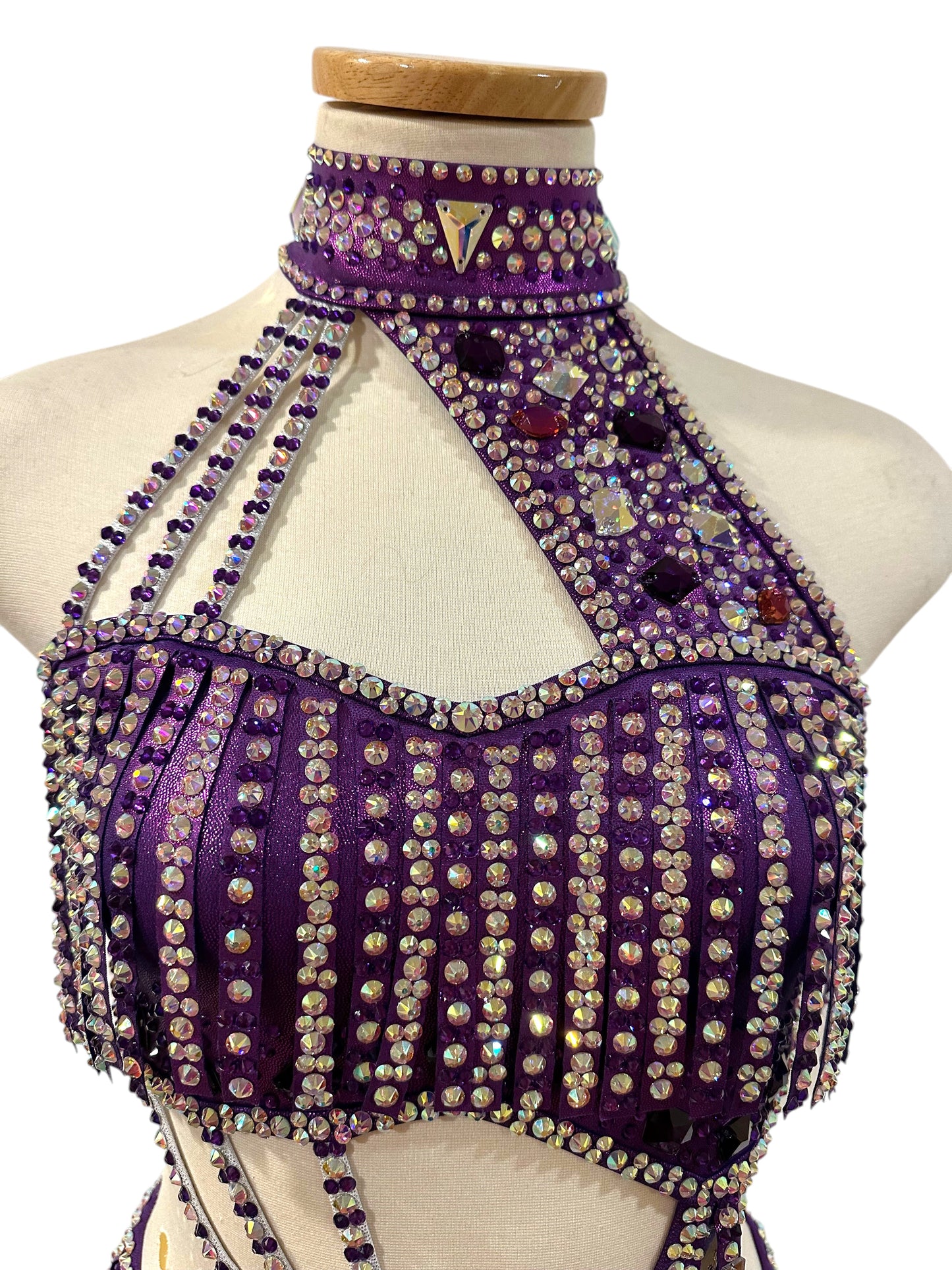 Close-up of hologram purple dance top and neckline, costume featuring mirror accents, rhinestone embellishments, and intricate competition costume detailing.