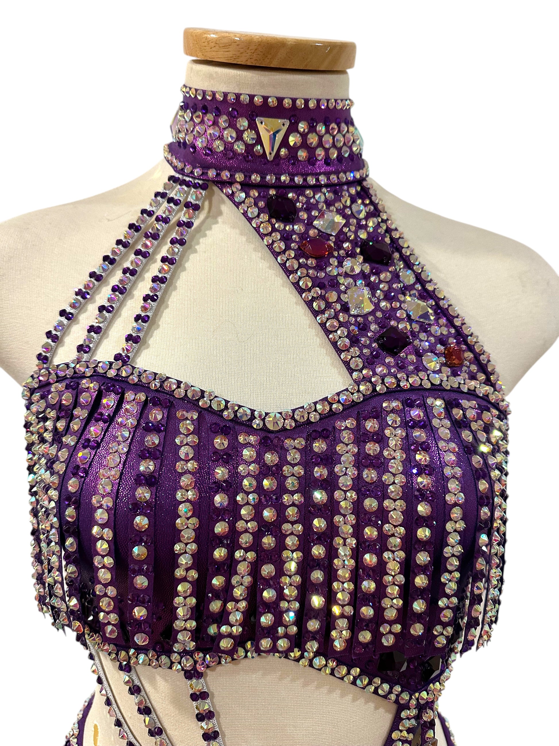 Close-up of hologram purple dance top and neckline, costume featuring mirror accents, rhinestone embellishments, and intricate competition costume detailing.