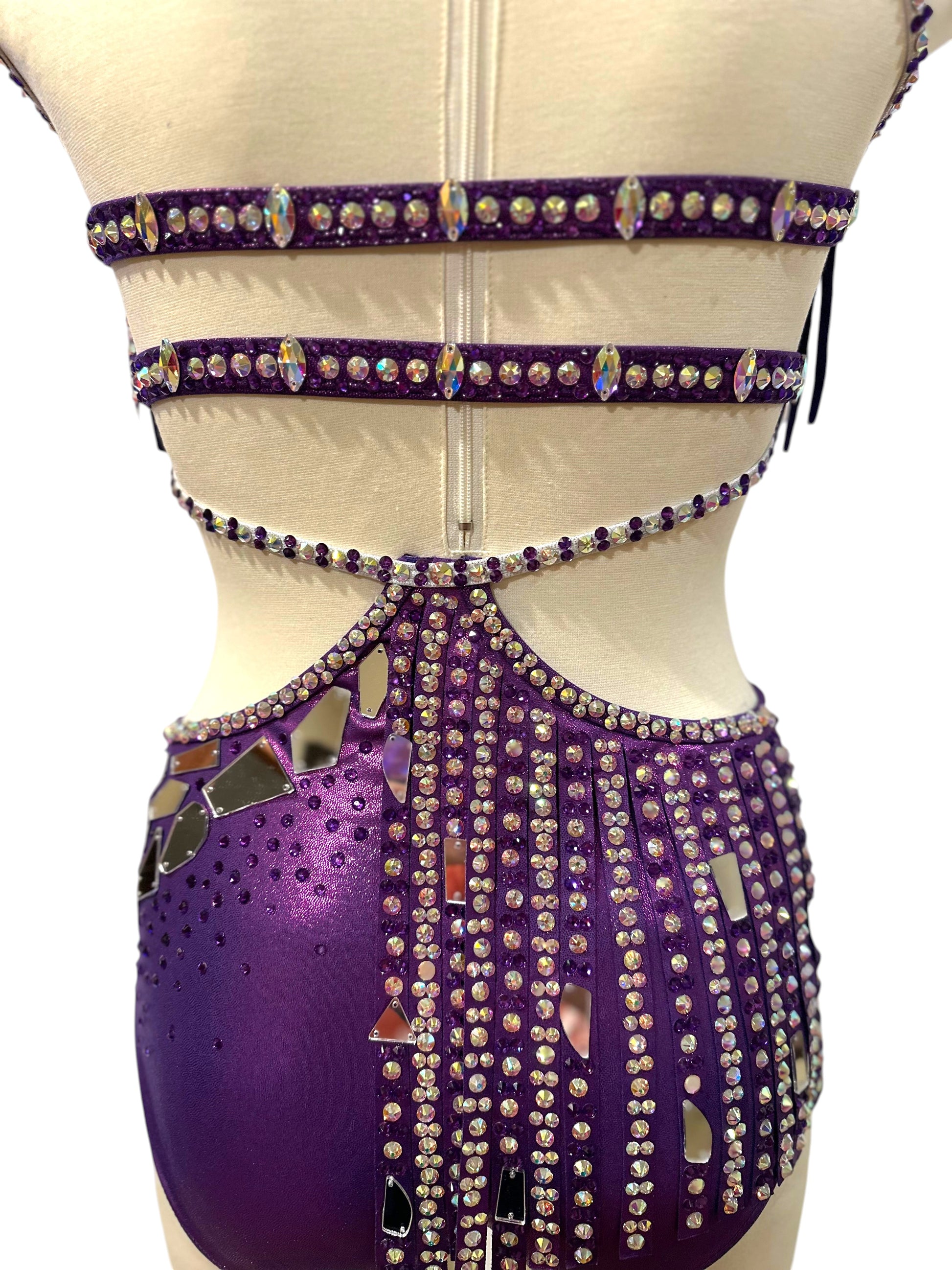 Close-up back view of purple dance costume highlighting strappy construction, rhinestone accents, and secure performance fit.