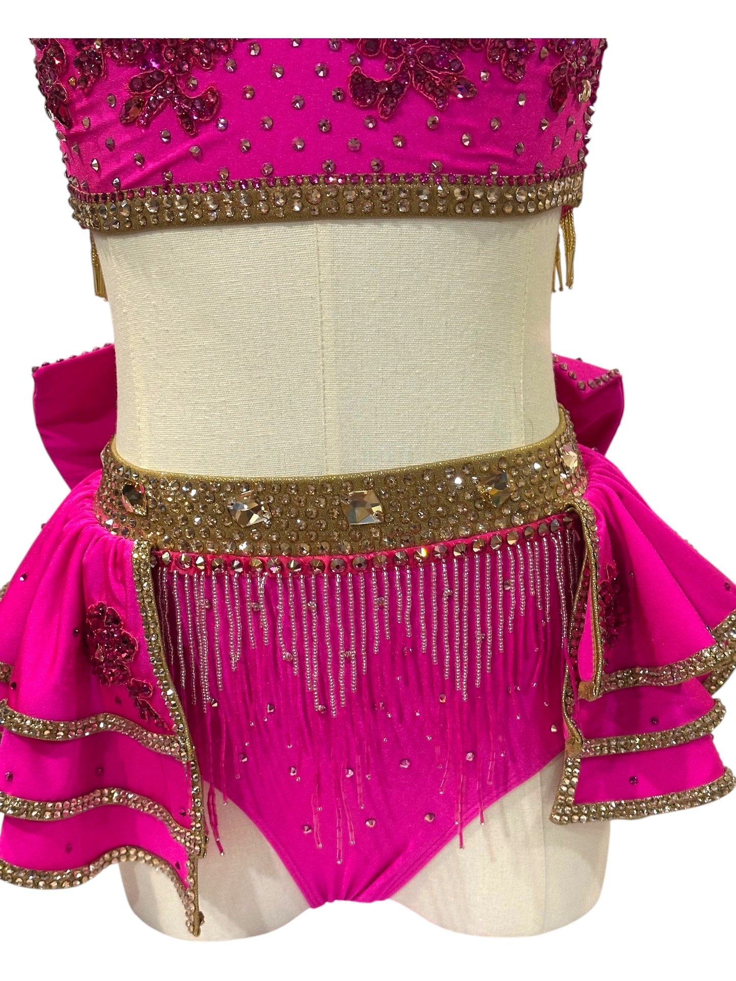Detail view of layered hot pink skirt accents with gold trim and sparkling rhinestone embellishments.