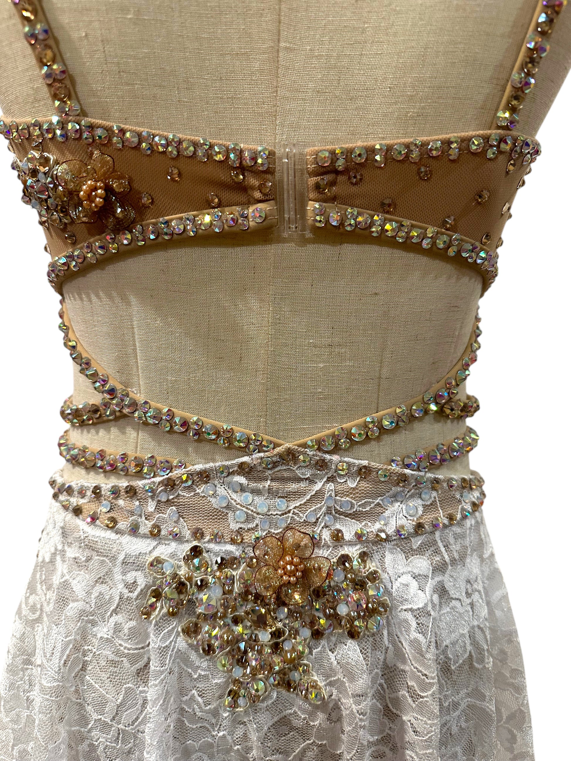 White lace dance costume back detail featuring crystal appliqué and strap design