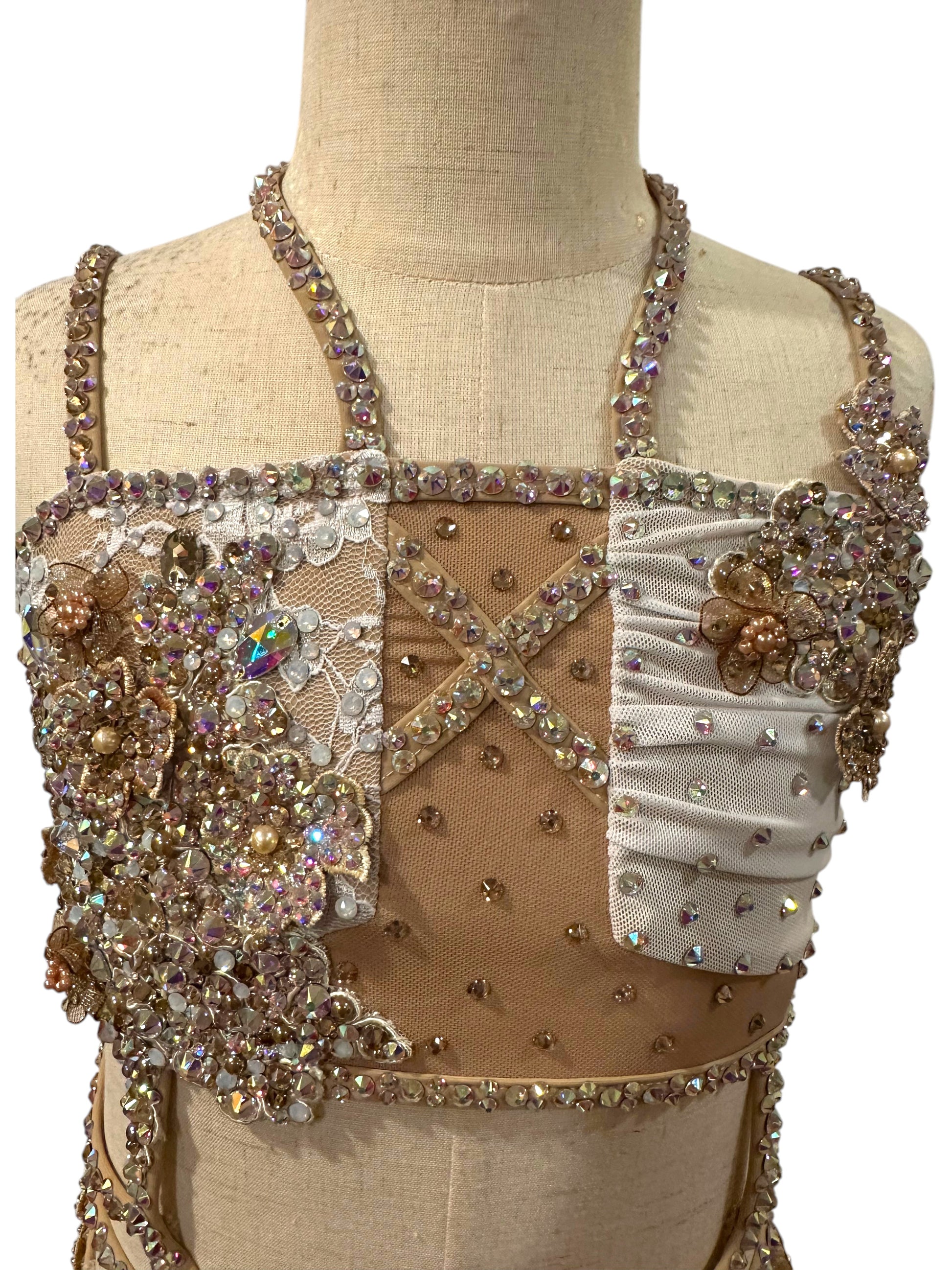 White lace competition costume front detail showing rhinestone appliqué and nude mesh panels