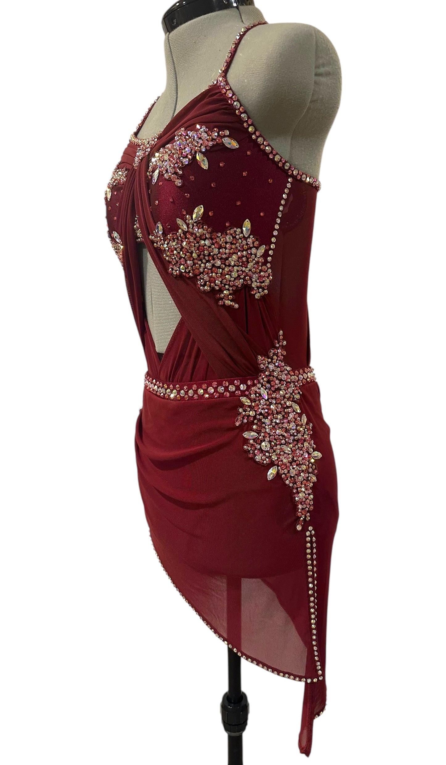 Angled view of ready-to-ship burgundy dance costume featuring rhinestone hip appliqué, open side detailing, and asymmetrical skirt