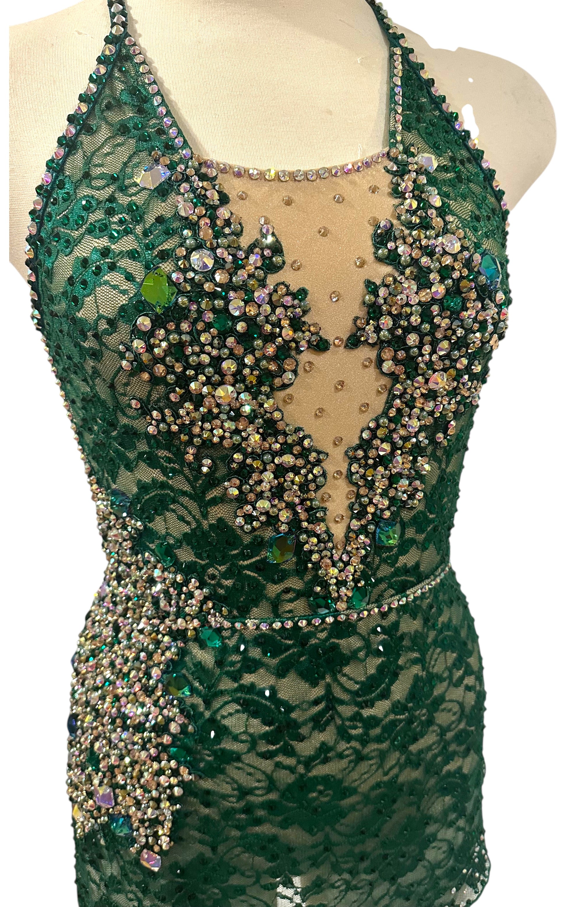 Close-up of emerald green rhinestone dance costume featuring lace overlay, crystal appliqué detailing, and nude illusion mesh neckline