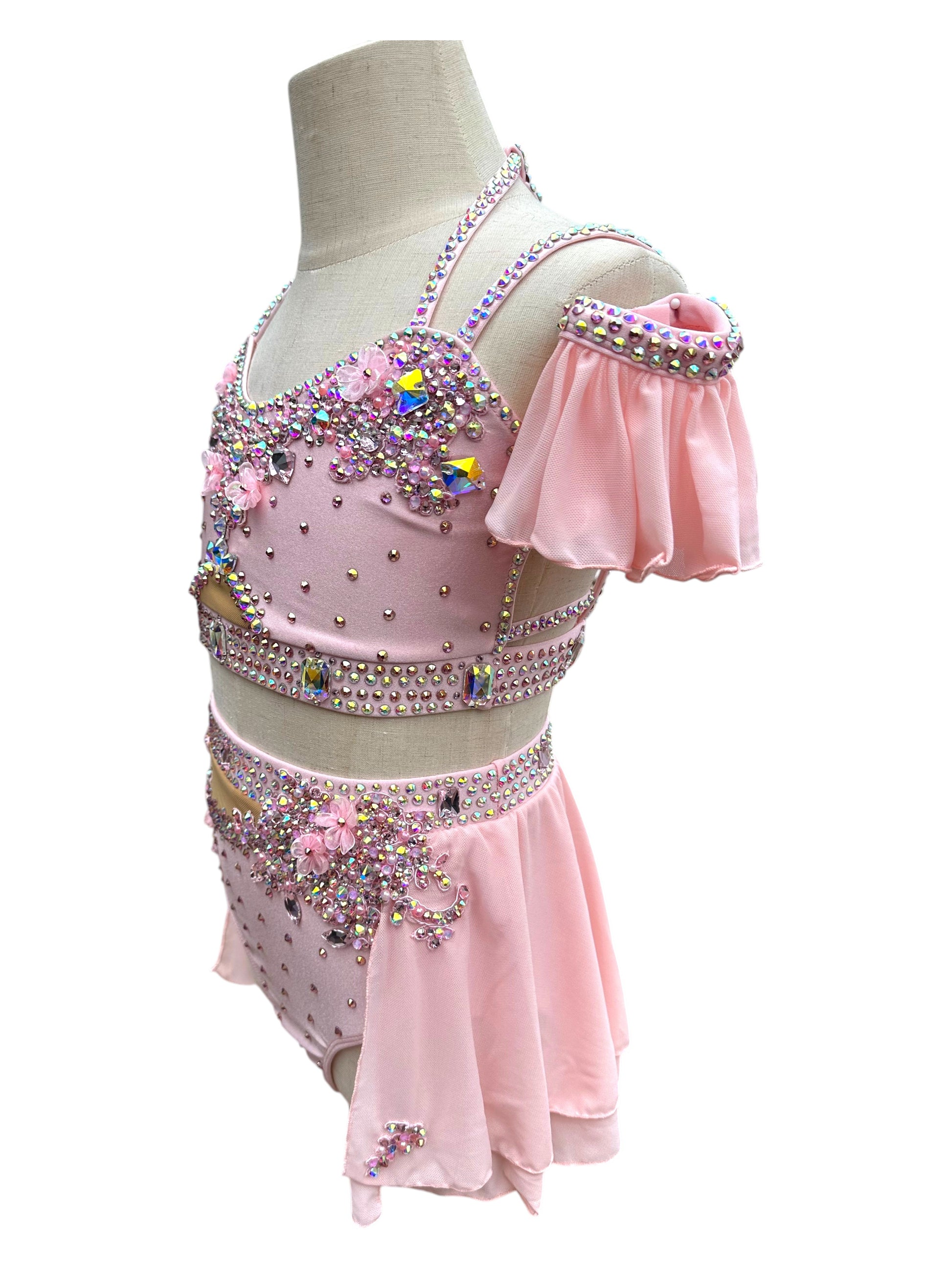 Side view of blush pink competition dance costume with rhinestones and floral appliqués