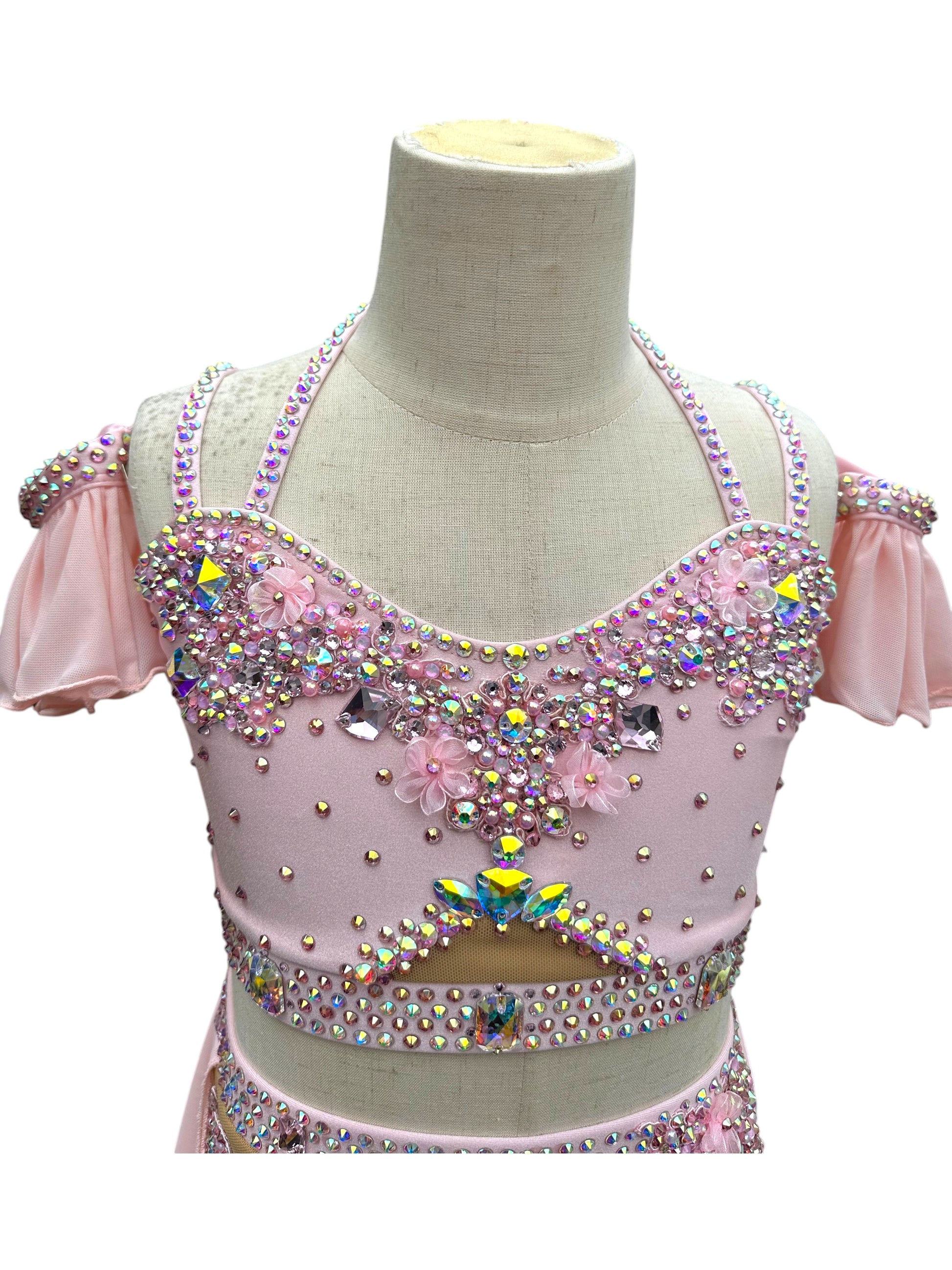 Close-up of blush pink dance costume bodice with AB rhinestones, crystals, and floral appliqués