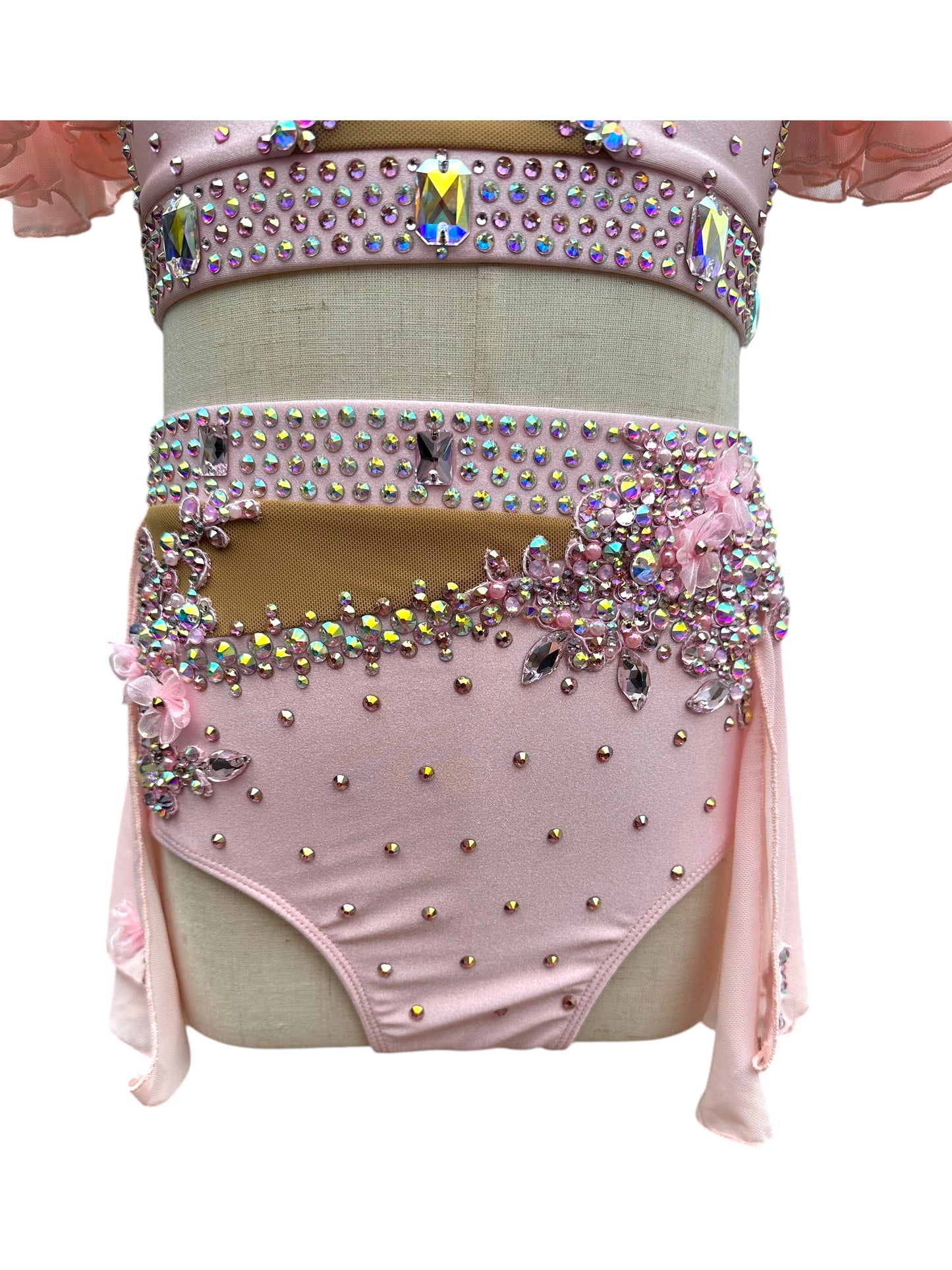 Close-up of blush pink dance costume bottom with rhinestone embellishments and floral detailing