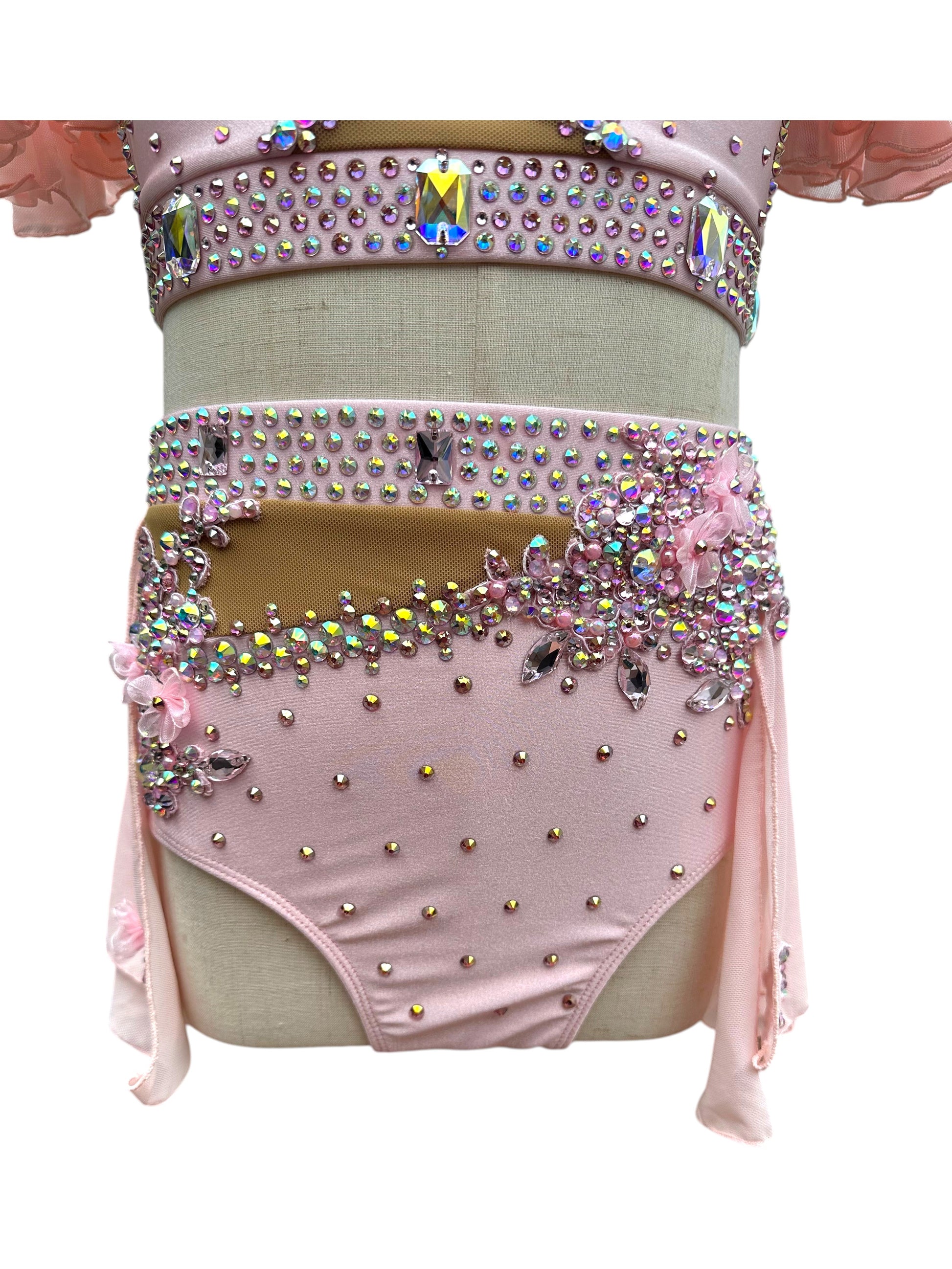 Close-up of blush pink dance costume bottom with rhinestone embellishments and floral detailing