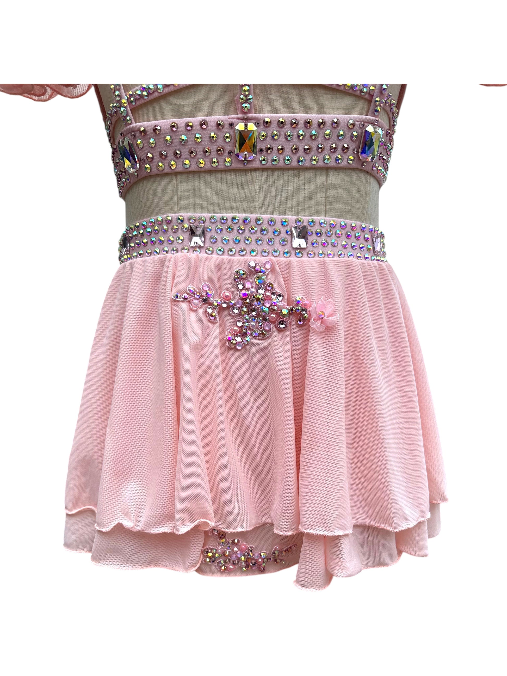 Close-up of back detail on blush pink dance costume featuring rhinestones and floral appliqués