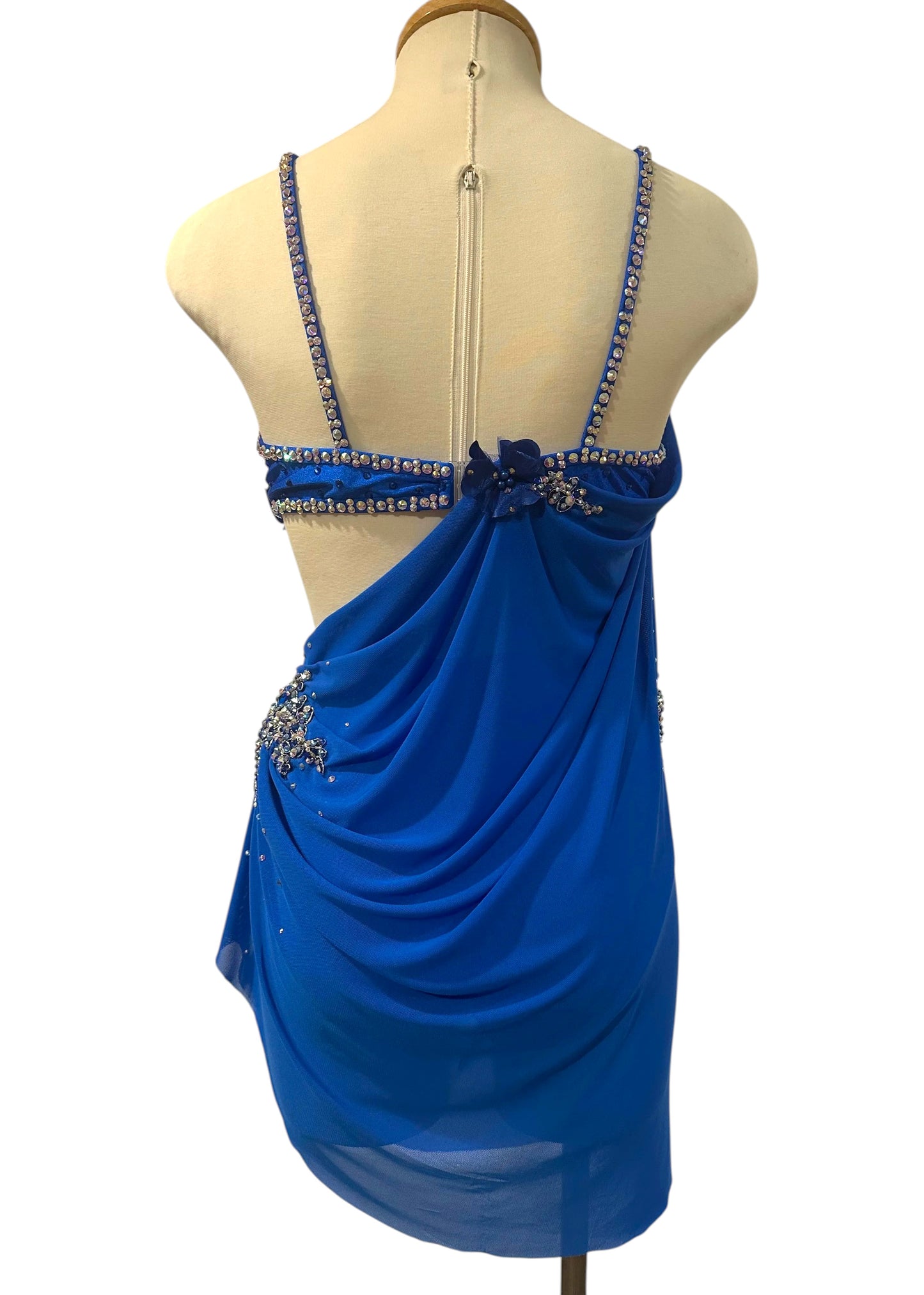 Back view of royal blue competition dance costume with elegant open back, crystal straps, and flowing mesh draping.