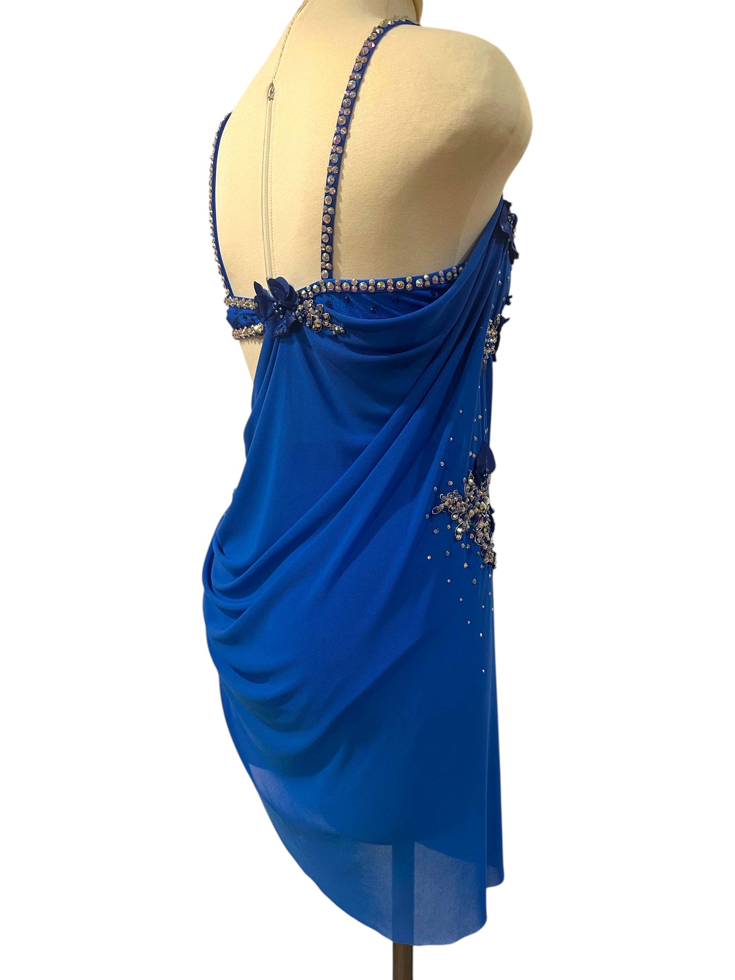 Rear angled view of royal blue rhinestone dance costume highlighting crystal accents, open back, and flowing draped fabric.