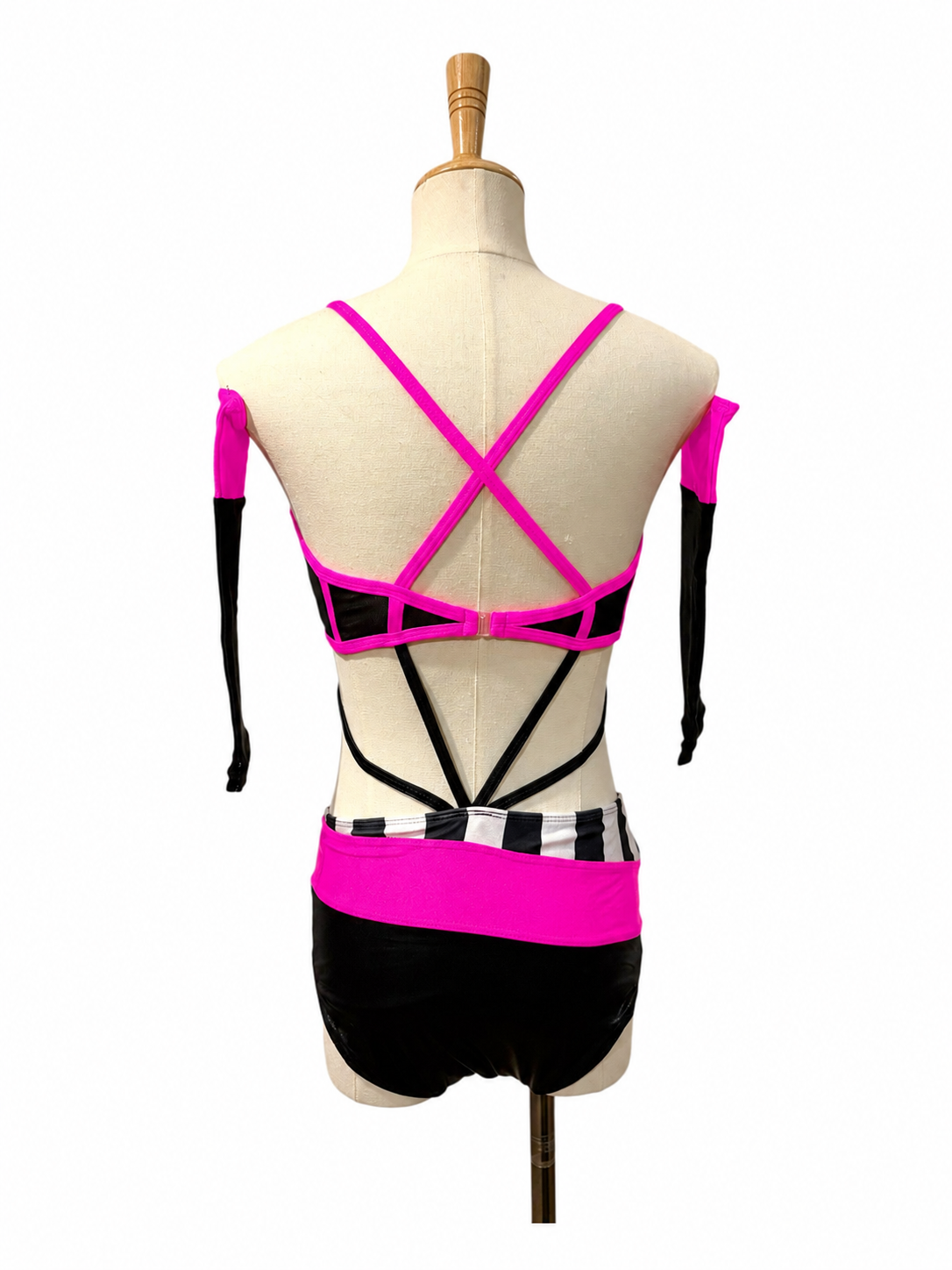 Back view of the Kat Base dance costume in hot pink showing crisscross straps, open back, and contemporary competition styling.