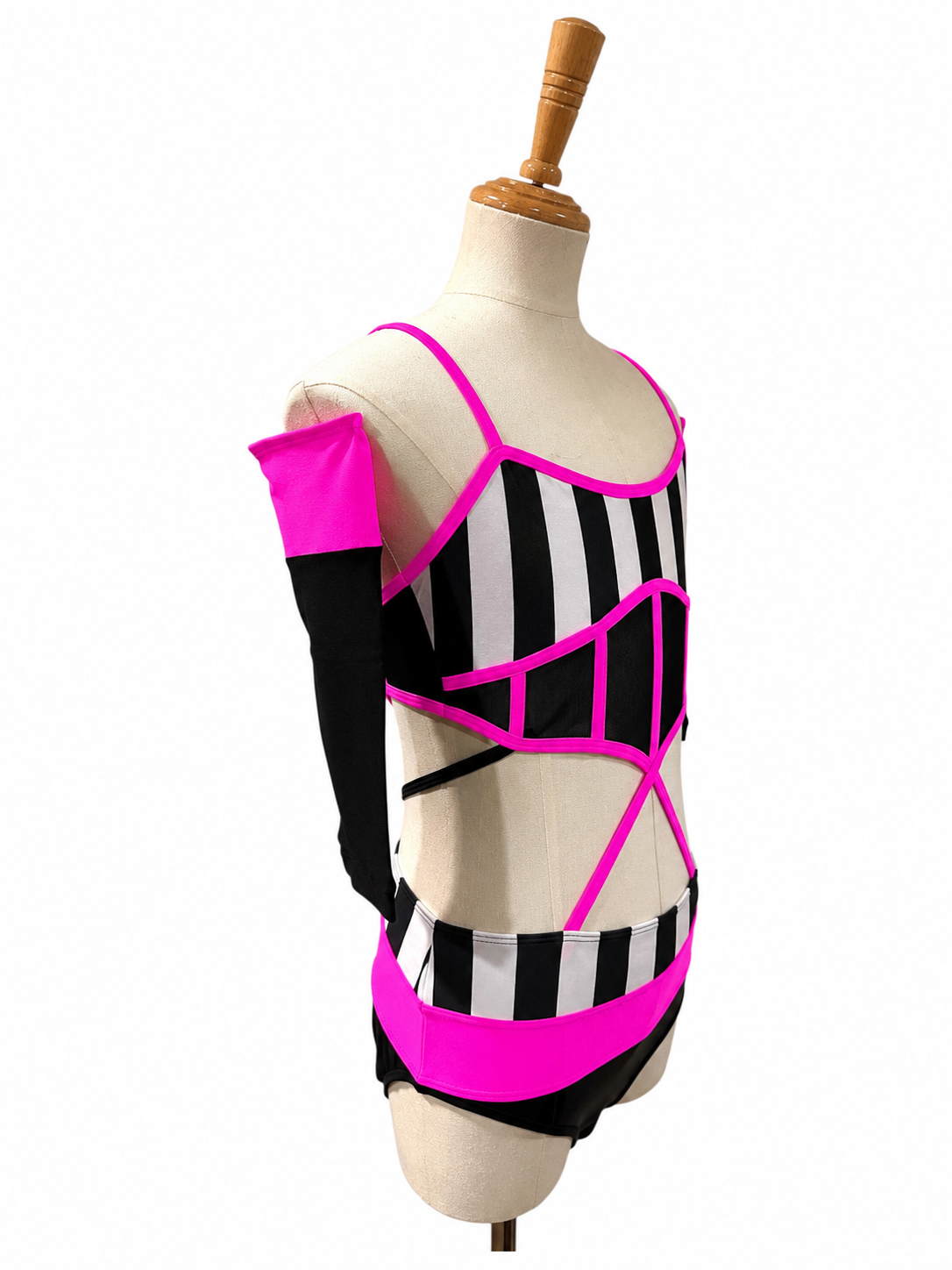 Angled view of the Kat Base competition dance costume in hot pink featuring striped bodice, illusion mesh, and modern cutout design.