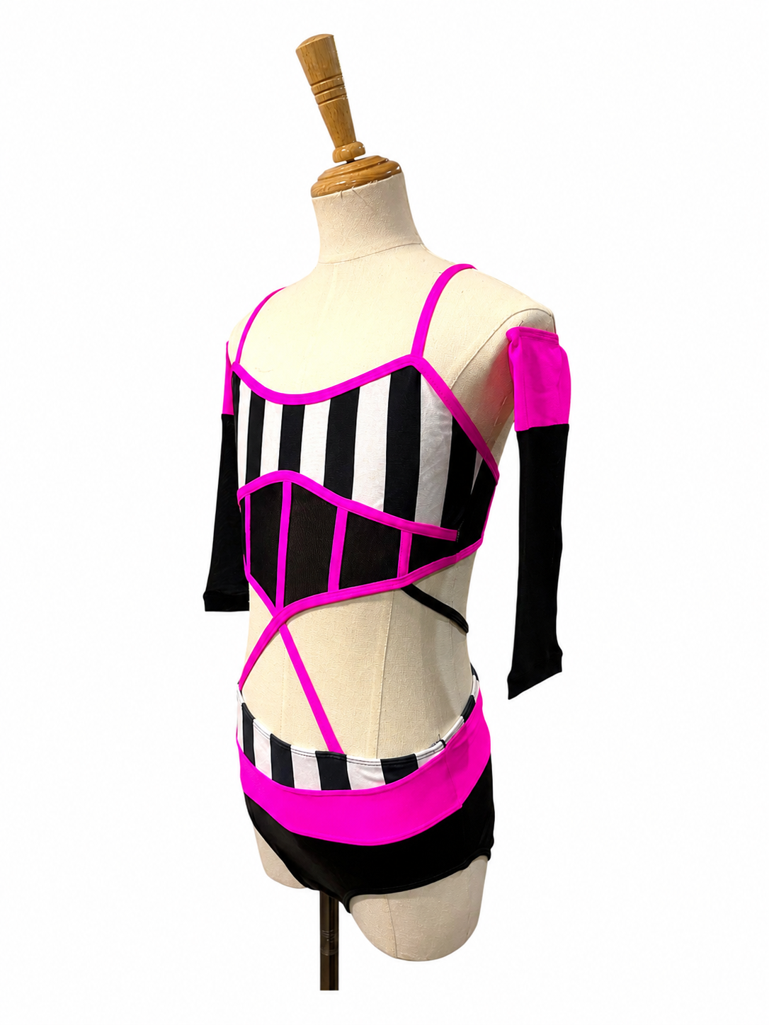 Left angled view of the Kat Base competition dance costume in hot pink featuring striped bodice, illusion mesh, and modern cutout design.