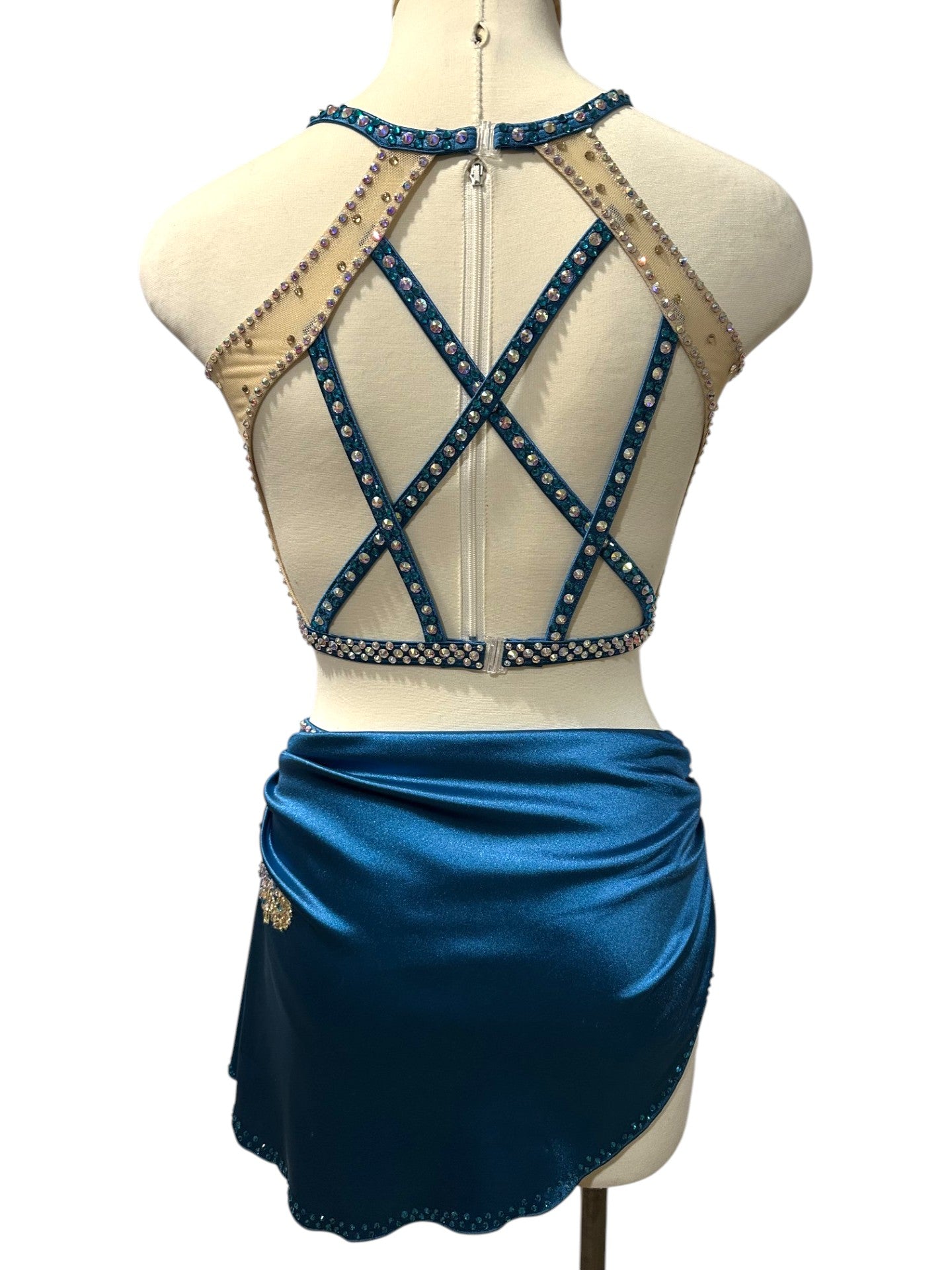 Back view of ready-to-ship peacock blue rhinestone dance costume featuring nude mesh panels, open back design, and crisscross crystal straps in Adult Small